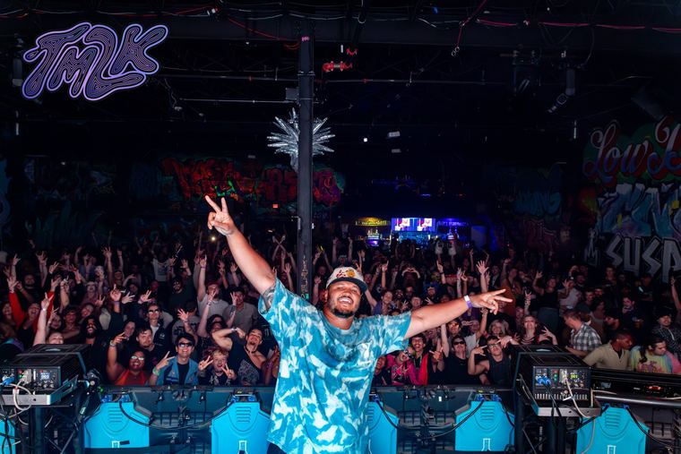 Cam throwing up peace signs on stage in front of a packed crowd