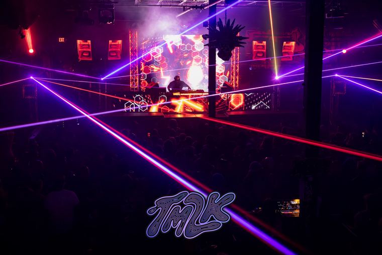 Purple and red lasers cutting across the room from the booth